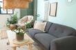 © Pixel-Shot - Cosy sofa and wooden coffee table with bamboo plant in living room