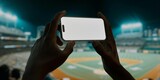 Fototapeta  - A hand holds a smartphone with a blank screen at a baseball stadium