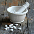 A white porcelain mortar and pestle with white pills 