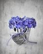 Purple hydrangea flowers and a wooden heart on a table. 