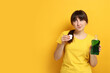 © New Africa - Young woman using mouthwash on yellow background, space for text