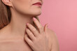 © New Africa - Woman touching her neck on pink background, closeup