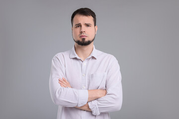 Wall Mural - Portrait of sad man with crossed arms on grey background