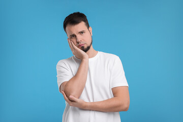 Wall Mural - Portrait of sad man on light blue background