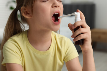 Canvas Print - Little girl using throat spray at home, closeup