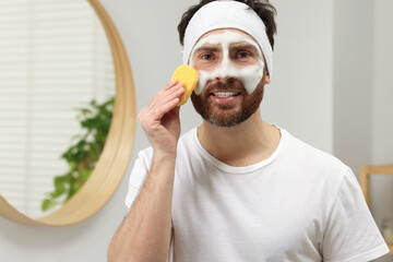 Sticker - Man with headband washing his face using sponge in bathroom