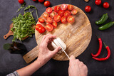 Fototapeta Na ścianę - Top view of the process of preparing fresh vegetable salad with mozzarella cheese on a wooden chopping board, flat lay