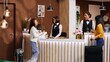 Asian friends arriving at hotel reception after travelling, waiting to check in and start city break vacation together. Two women guests receiving excellent concierge services from front desk staff.