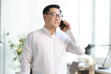 Canvas Print - Portrait of smiling businessman talking by smartphone in office