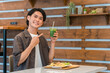 カフェでランチを食べながらグリーンスムージーを飲む若い男性（酵素・デトックス・食物繊維・健康食品）
