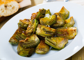 Wall Mural - Delicious oil-fried cut artichokes served on plate. Healthy food..