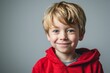 Portrait of a cute little blond boy in a red hoodie