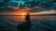 © engkiang - Man meditating on a rock in the sea at sunset or sunrise