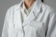 A person wearing a white lab coat with a blank identification badge attached to the chest.