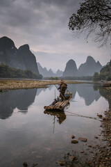 Wall Mural - Cormorant fisherman and his bird on the Li River in Yangshuo, Guangxi, China.