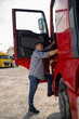 Vertical image, man truck driver entering the truck, beautiful sunny day