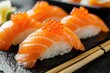 A close-up shot of salmon nigiri sushi with bright orange roe and a dollop of creamy wasabi paste.