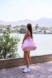 Young woman enjoying lakeside view with pink bag