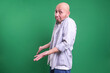 © Gatot - Bald Man Gesturing Confuse and Showing Helpless Gesture Shrugging Shoulder Isolated on Green Background. I don't know.