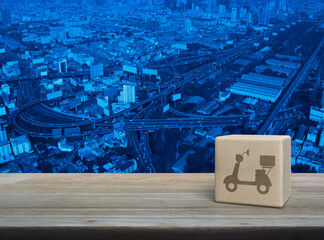 Canvas Print - Motorcycle icon on wood block cube on wooden table over modern city tower, street, expressway and skyscraper, Business delivery service concept