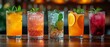   A row of glasses, each holding a distinct drink, garnished with slices of lime, orange, and mint