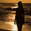 Silhouette of a woman walking along the beach at sunrise or sunset