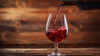 Red wine flows from the bottle into the glass against a wooden backdrop.