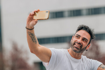 Wall Mural - portrait of attractive man with beard outdoors making selfie with mobile phone