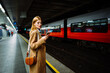 © Big Shot Theory - Young serious businesswoman in suit surfing wireless internet on smartphone in metro