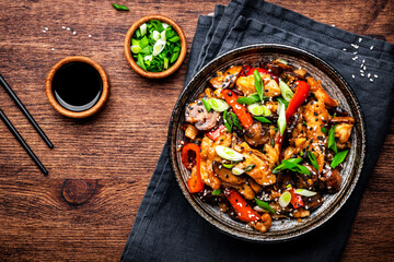 Wall Mural - Stir fry turkey slices with red paprika, mushrooms, chives and sesame seeds with ginger, garlic and soy sauce. Old wooden table background, top view