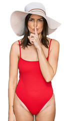 Poster - Beautiful brunette woman wearing swimsuit and summer hat asking to be quiet with finger on lips. silence and secret concept.