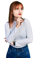 Poster - Redhead young woman wearing casual turtleneck sweater with hand on chin thinking about question, pensive expression. smiling with thoughtful face. doubt concept.