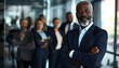 Business Black man leader standing in office at team meeting, business man standing in office with work colleagues. Confident man in formal wear stands at her workplace