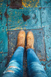 Top view photo of legs in jeans and feet in suede shoes on wet asphalt