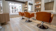 Interior of a modern barber shop with orange chairs and tables