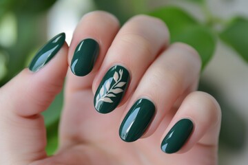 Close-up of hand with minimalist green nail polish and delicate leaf design on one finger