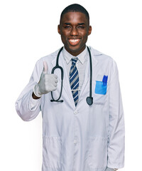 Wall Mural - Young african american man wearing doctor uniform and stethoscope smiling happy and positive, thumb up doing excellent and approval sign