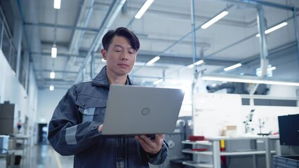 Leinwandbilder - Portrait of an Asian Industrial Specialist Standing in Electronics Manufacturing Facility and Using Laptop Computer. Professional Technician Thinking About Daily Tasks and Browsing Data Online