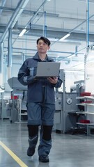 Leinwandbilder - Vertical Screen: Asian Engineer Using a Laptop Computer on the Go at Electronics Manufacturing Factory. Adult Technician Working on Daily Tasks and Analyzing New Production Plans