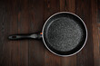 Metal frying pan: Ceramic coating with non-stick coating: Kitchen utensils; On a wooden background: Cooking for chefs in the kitchen.A place for the text.