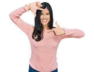 Wall Mural - Young hispanic woman wearing casual clothes smiling making frame with hands and fingers with happy face. creativity and photography concept.