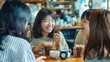 Cheerful asian young women sitting in cafe drinking coffee with friends and talking together
