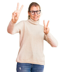 Wall Mural - Young beautiful blonde woman wearing turtleneck sweater and glasses smiling looking to the camera showing fingers doing victory sign. number two.