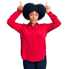 Poster - Young african american girl wearing casual clothes doing funny gesture with finger over head as bull horns