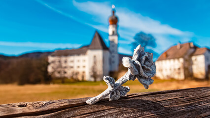 Wall Mural - Details of a stone rose with a monastery in the background at Lake Hoeglwoerther See, Anger, Rupertiwinkel, Berchtesgadener Land, Bavaria, Germany