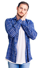 Wall Mural - Young handsome caucasian man wearing casual clothes sleeping tired dreaming and posing with hands together while smiling with closed eyes.