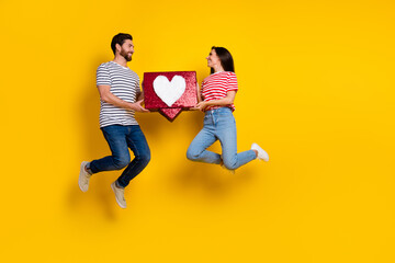 Wall Mural - Full length photo of funny couple wear striped t-shirt hold big social media like in palms isolated on vivid yellow color background