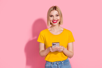 Wall Mural - Photo of positive good mood lady dressed yellow t-shirt texting modern gadget isolated pink color background