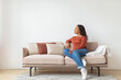 © Prostock-studio - Black Woman Sitting on Couch in Living Room