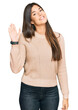 © Krakenimages.com - Young brunette woman wearing casual winter sweater waiving saying hello happy and smiling, friendly welcome gesture